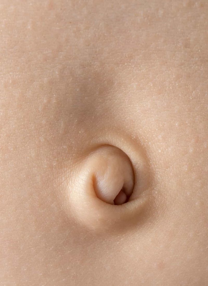 Close-up of a baby navel with delicate skin in soft lighting, highlighting the texture.