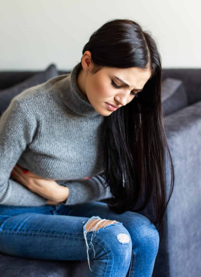Sick brunette having stomachache in the living room